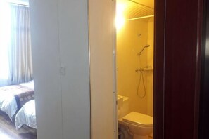 Kylpyhuoneessa on suihku ja wc, ja viereisessä huoneessa on sänky.