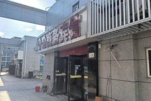 A hotel entrance with a signboard, a glass door, and a metal railing. - Ningbo Jinhui Business Hotel (Ningbo)