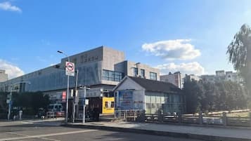 A modern building with a large glass facade, a no parking sign, and a small adjacent structure with a sign.