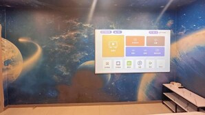 A room with a space-themed mural on the walls, a projection screen displaying icons, and a seating area with tables. - Ningbo Jinhui Business Hotel (Ningbo)