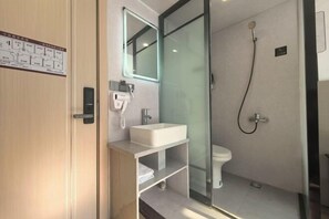 Un baño moderno con cabina de ducha de vidrio, un lavamanos blanco y un inodoro.