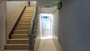 A staircase with a handrail leading to a hallway with a green exit sign. - Ningbo Jinhui Business Hotel (Ningbo)