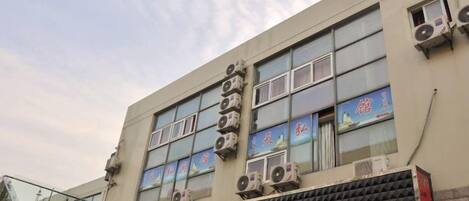Un bâtiment doté de plusieurs unités de climatisation, une enseigne avec des caractères chinois et une vitrine sur laquelle on peut lire le mot « JACK ».