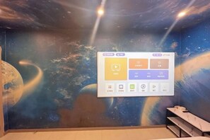 A room with a space-themed mural, a projection screen displaying icons, and a seating area with tables. - Ningbo Jinhui Business Hotel (Ningbo)