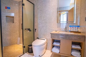 Ein modernes Badezimmer mit einer Duschkabine, einer Toilette und einem Waschtisch mit Handtüchern.