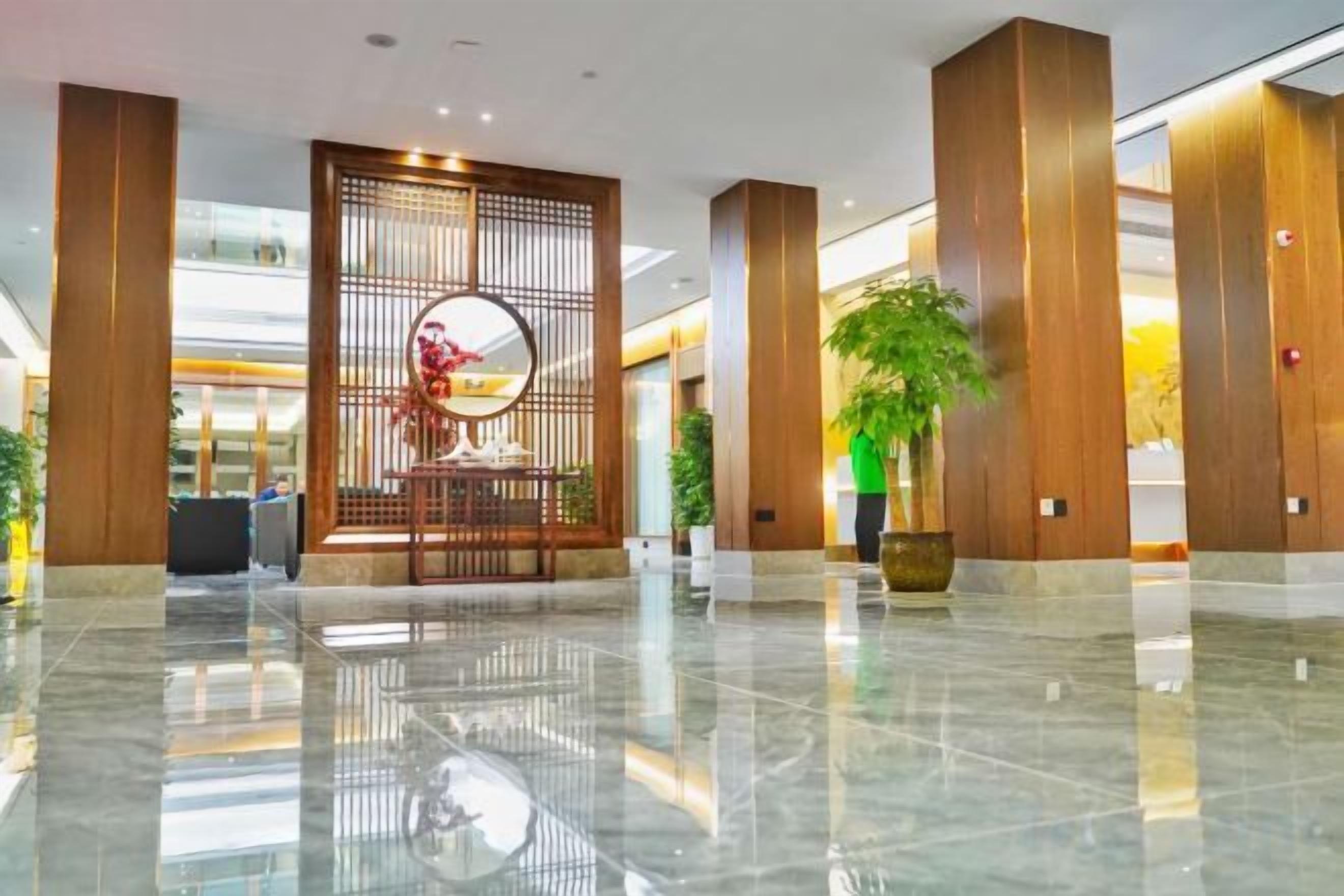 A modern lobby with a polished marble floor, a reception desk, and a decorative wall with a circular mirror.
