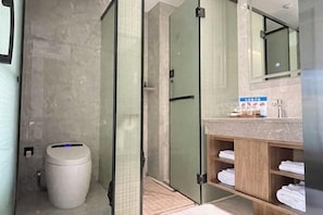 A modern bathroom with a glass shower enclosure, a toilet, and a vanity with a mirror and towel storage. - egret land Hotel (Chongqing)