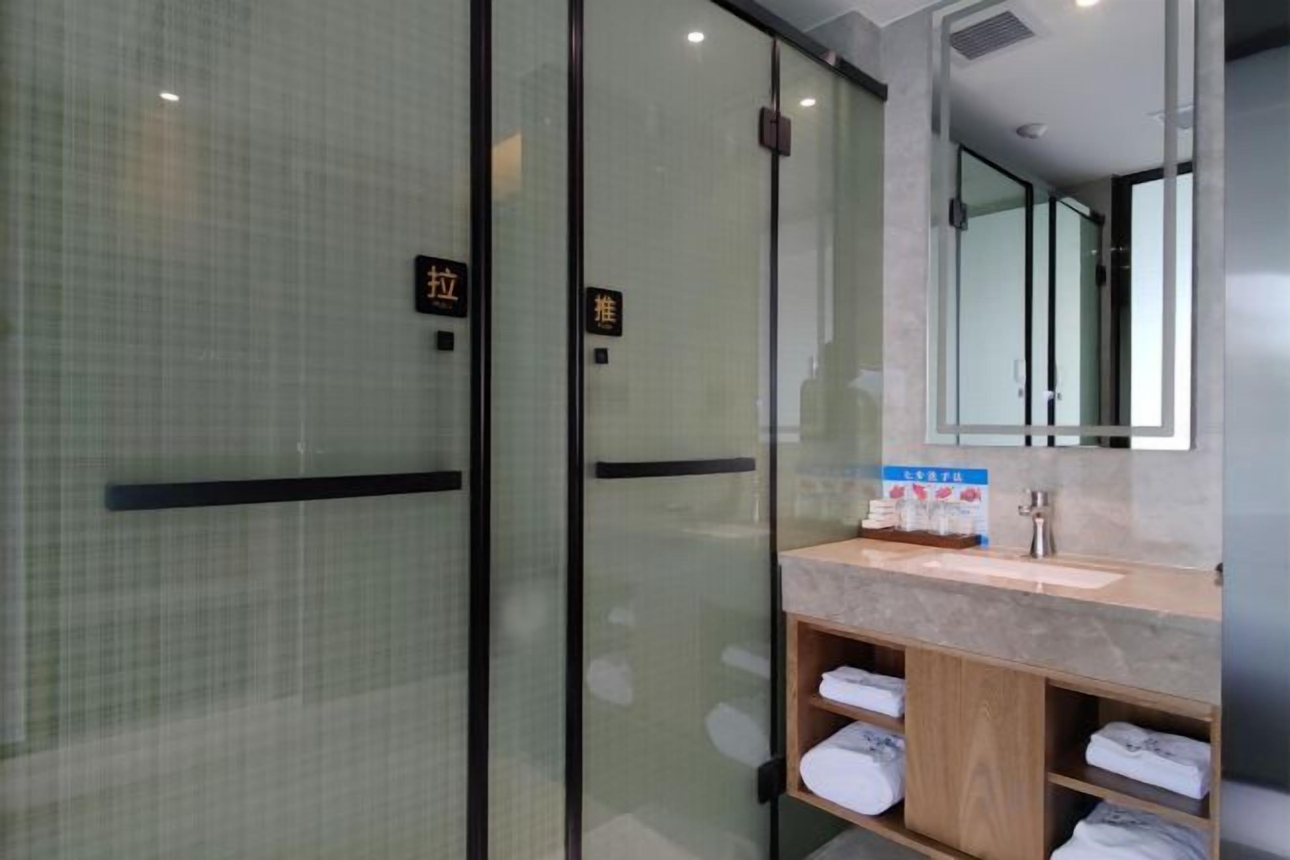 Un bagno d'hotel con box doccia in vetro, lavabo con specchio e porta asciugamani.