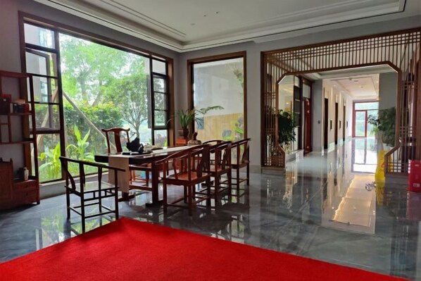 A spacious room with a dining area, large windows, and a view of greenery outside. - egret land Hotel (Chongqing)