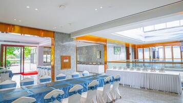 Un salón de conferencias con mesas dispuestas para una reunión, un panel de vidrio y vistas al exterior.