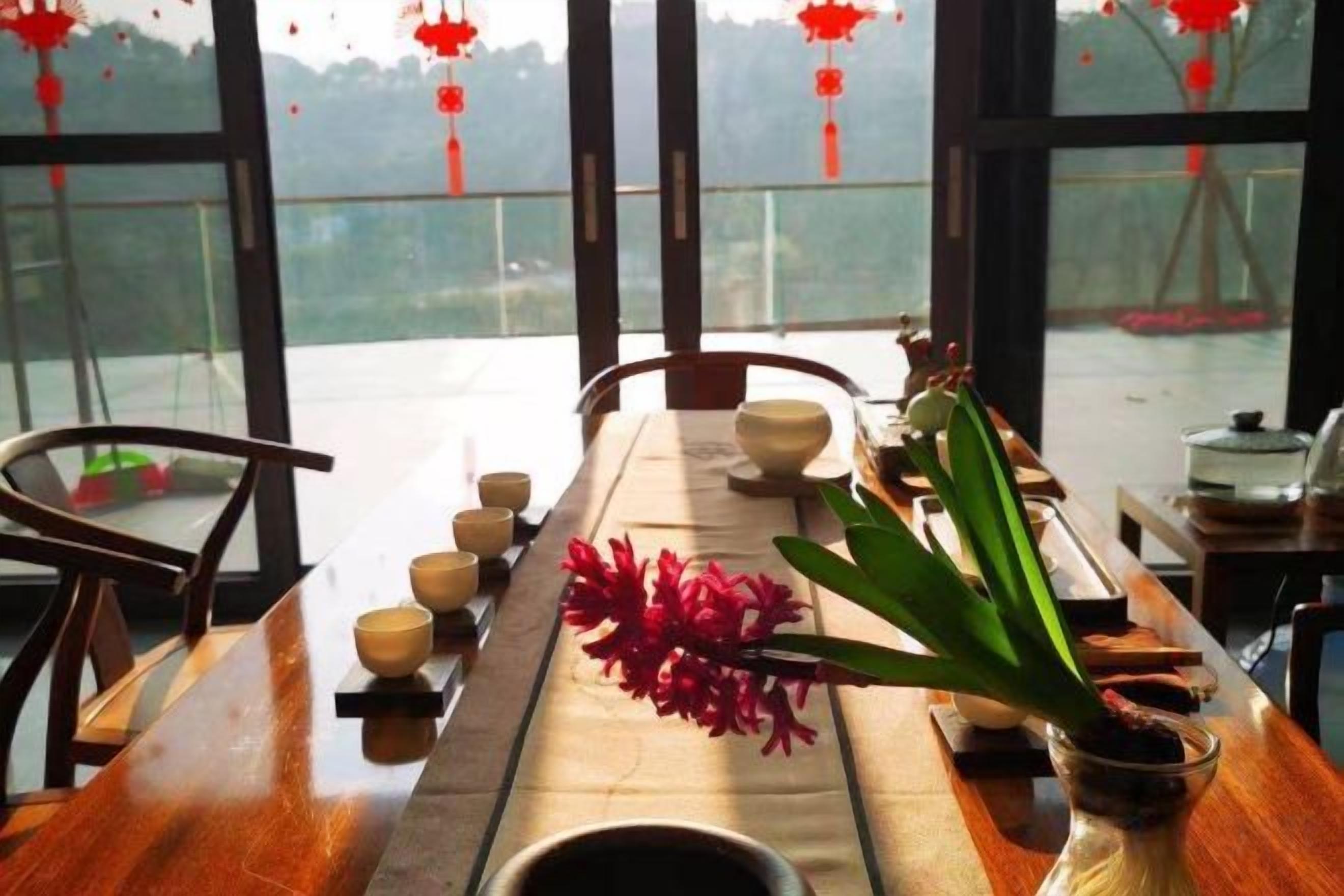 A dining table with a vase of flowers, bowls, and chopsticks.