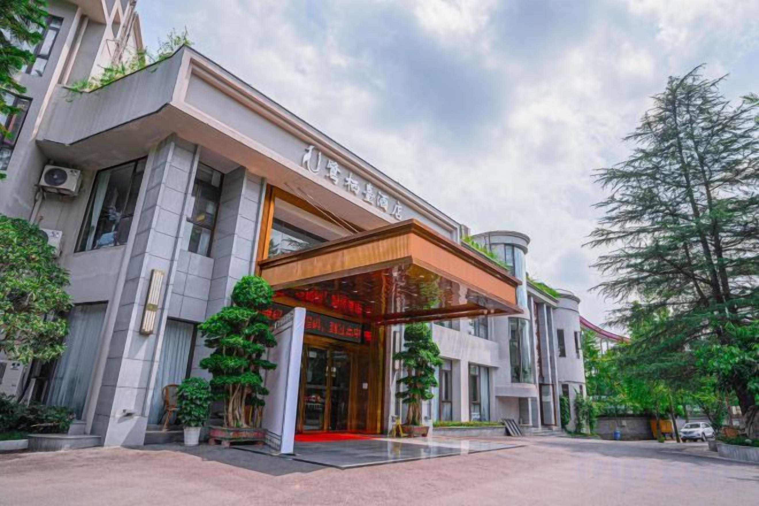 Entrada d'hotel amb un disseny modern, una zona d'accés coberta i una catifa vermella que condueix a l'interior.