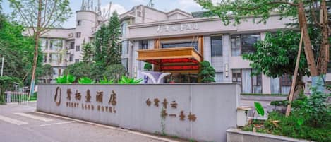 A hotel entrance with a modern facade, a prominent entrance canopy, and a landscaped area with greenery.