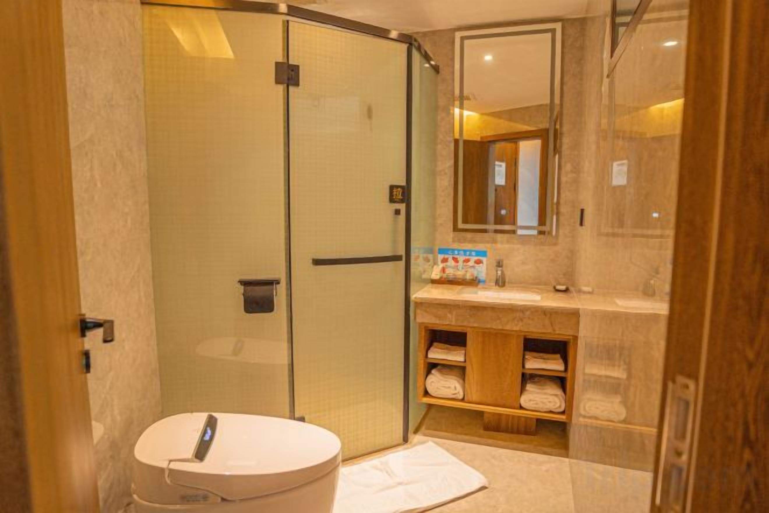 A bathroom with a glass-enclosed shower, a round sink, and a vanity with a mirror.