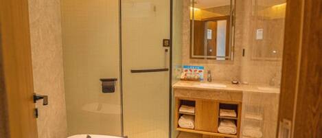 A bathroom with a glass-enclosed shower, a round sink, and a vanity with a mirror.