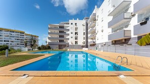 Un immeuble d’appartements moderne doté d’une piscine, de balcons et surplombant un ciel d’un bleu éclatant.