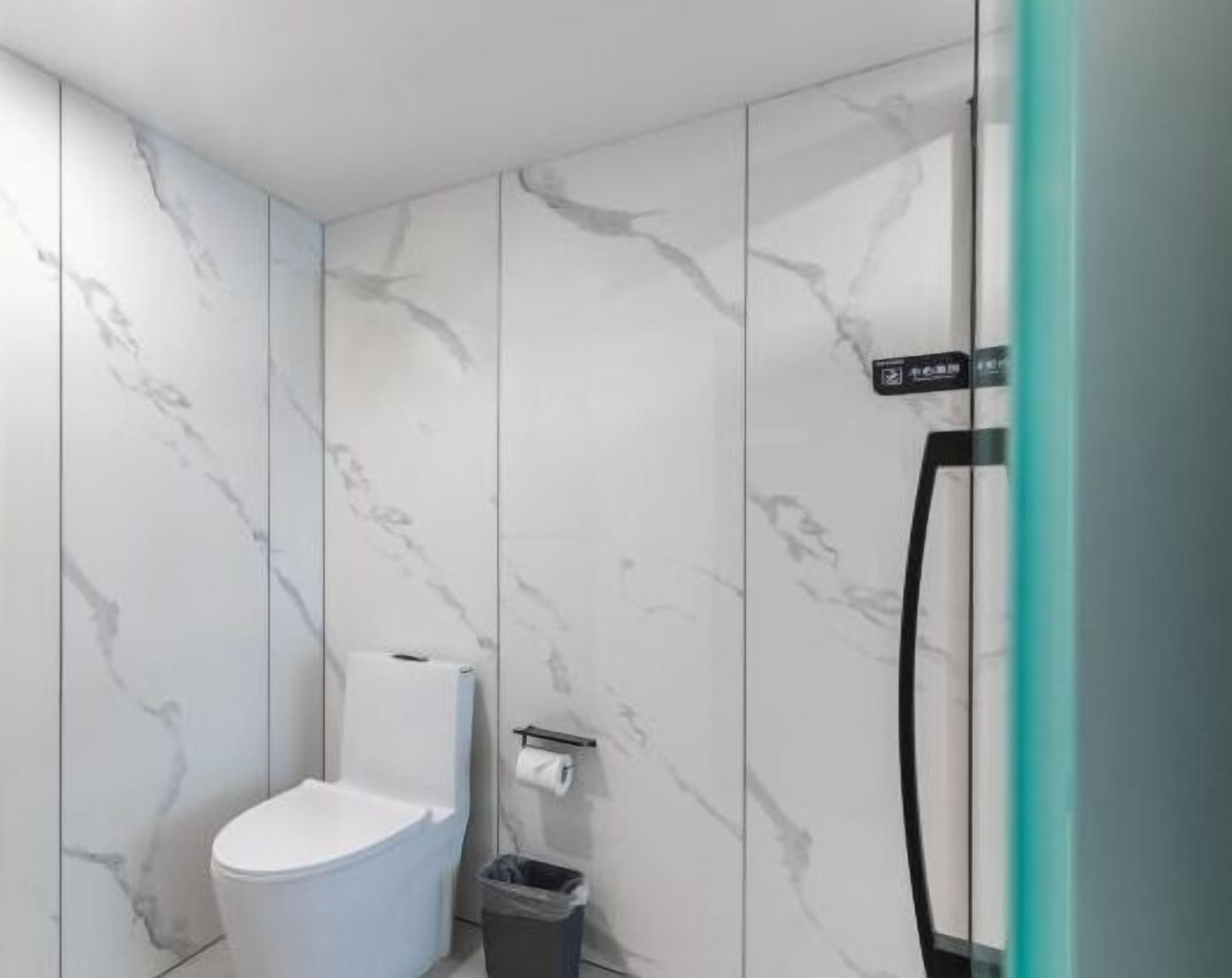 Un baño con inodoro, un cubo de basura y zona de ducha.