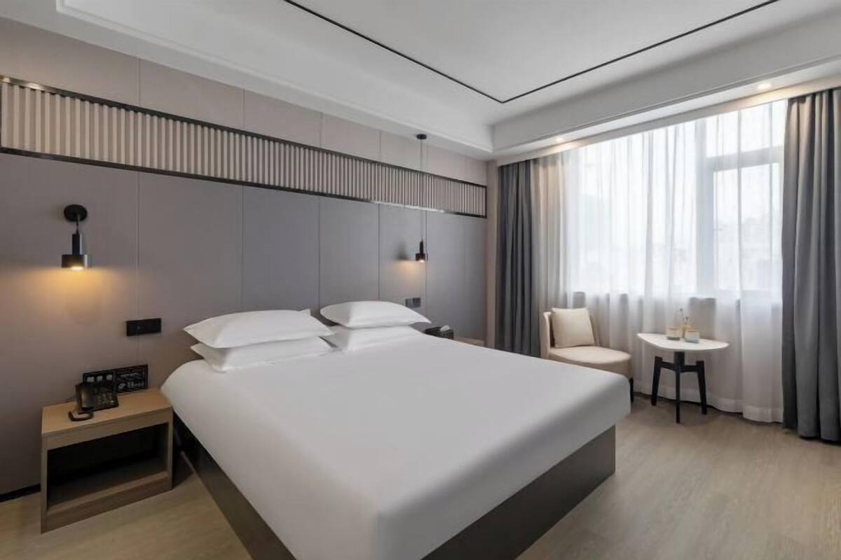 Une chambre d’hôtel moderne avec un grand lit, des tables de chevet, une petite table et une chaise.
