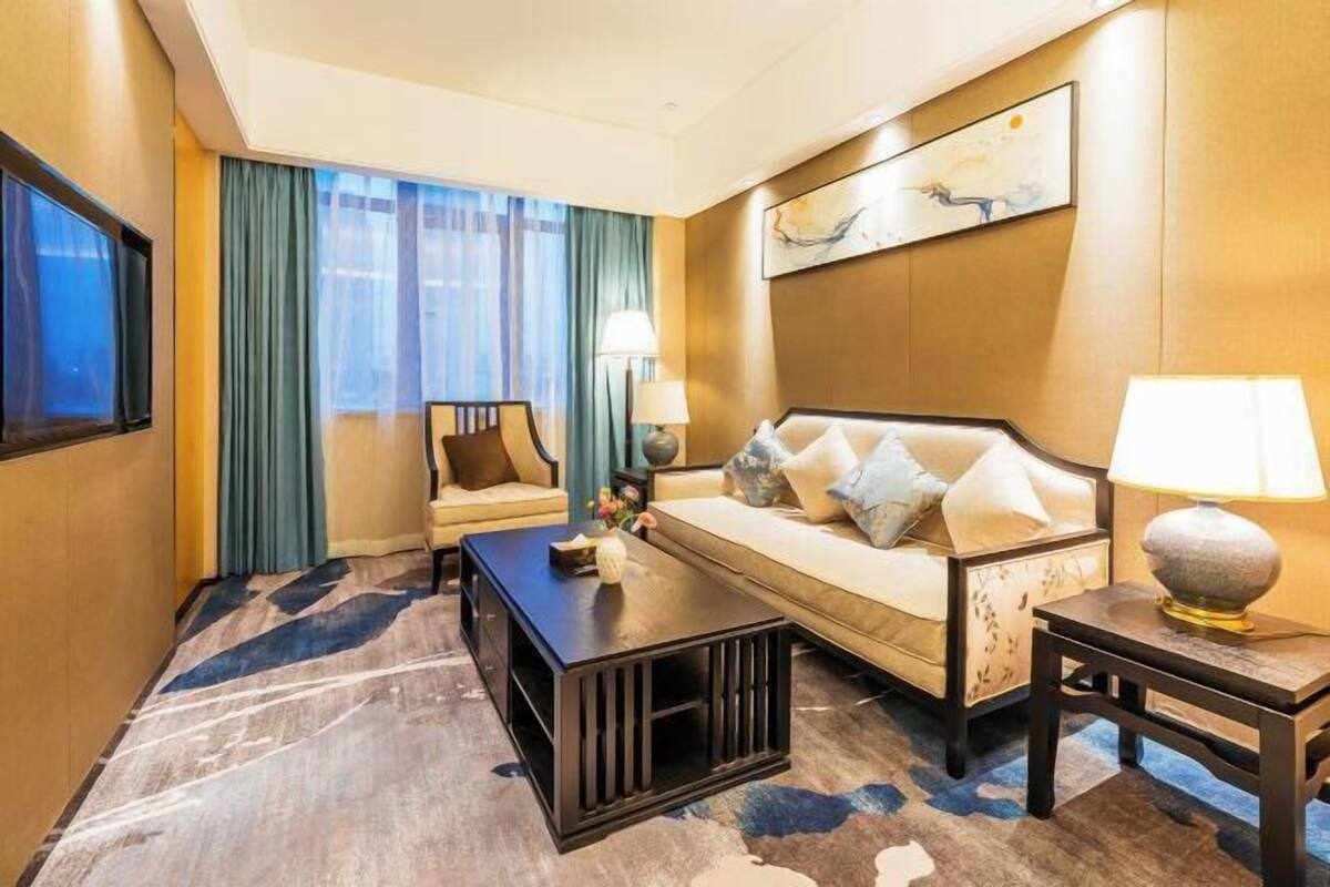 Une chambre d’hôtel avec un canapé, une table basse, un téléviseur et un tableau au mur.