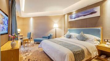 A hotel room with a large bed, a desk, a chair, a TV, and a painting on the wall.