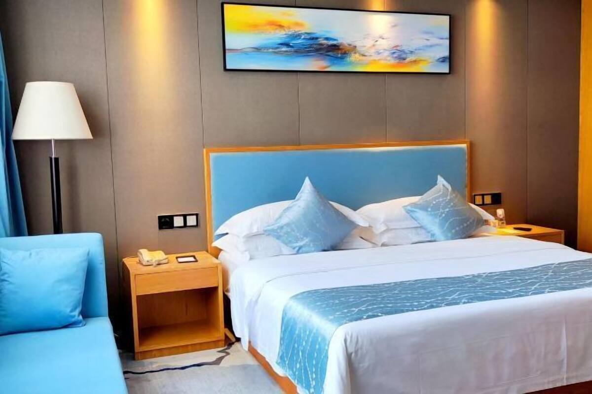 Une chambre d’hôtel avec un lit, une table de chevet, une lampe et un tableau au mur.