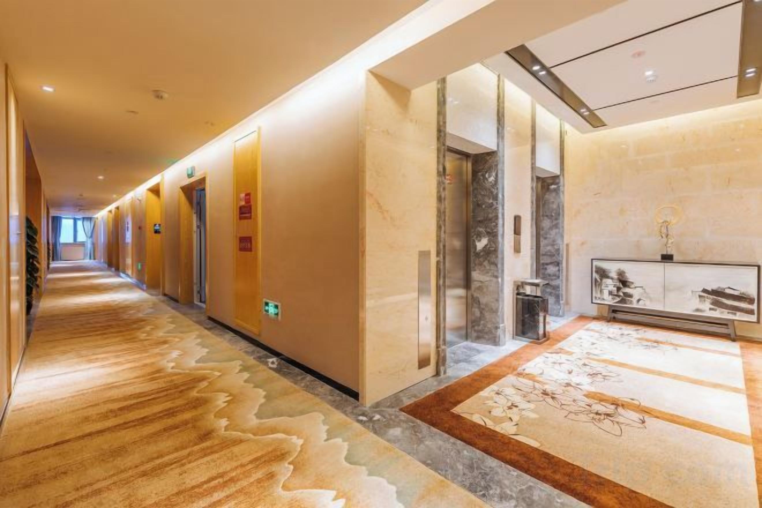 A hotel corridor with a carpeted floor, doors, and a reception area with a marble counter.