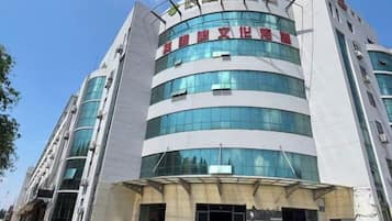 A multi-story building with a modern architectural design, featuring a prominent entrance with glass doors and a sign above.