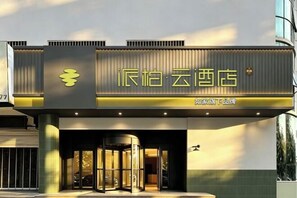 A hotel entrance with a revolving door, a sign with Chinese characters, and a modern architectural design. - Home Inn Paibai Yun Hotel (Qingdao Jiaonan Haier Industrial Park Branch) (Qingdao)