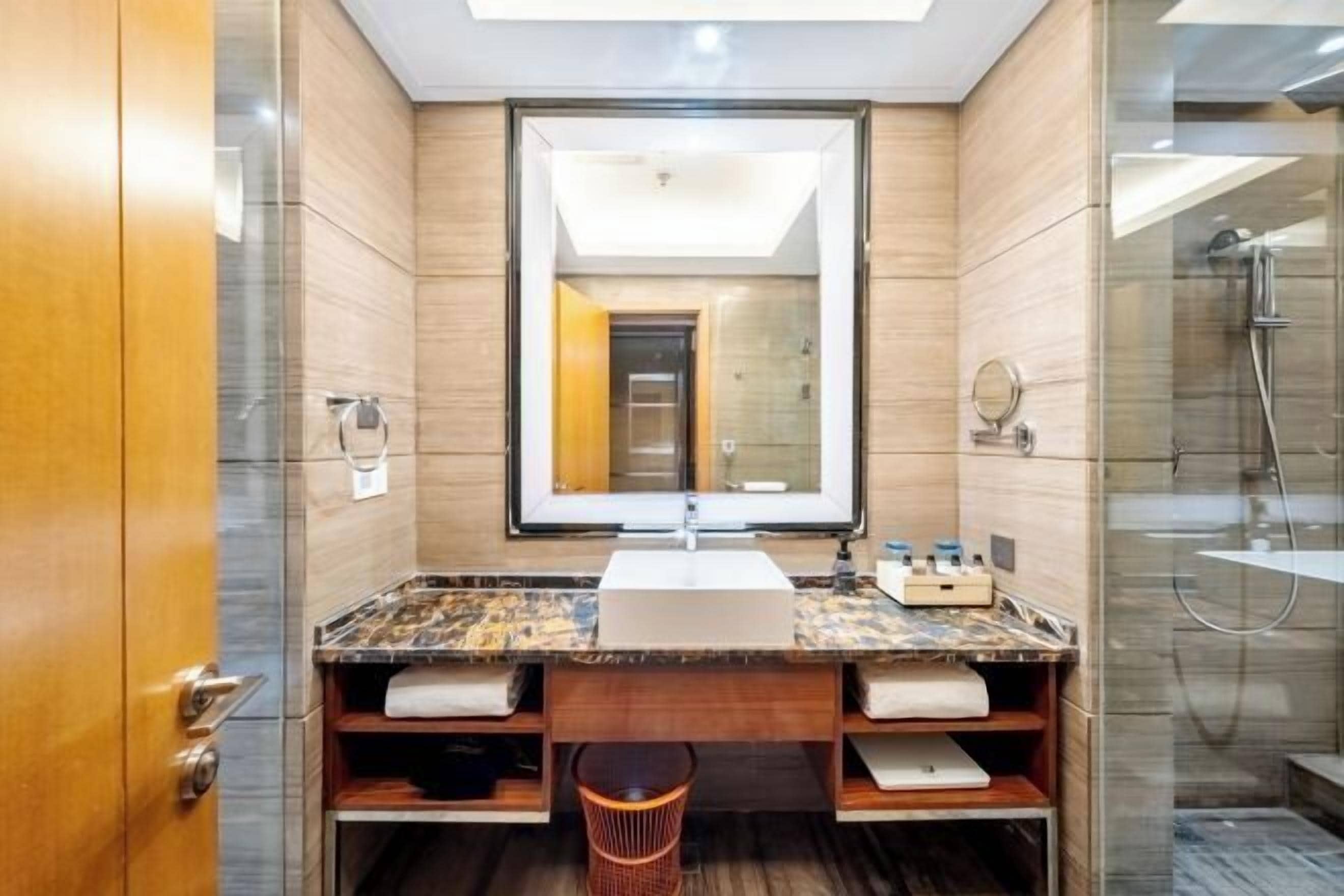 Une salle de bain moderne avec un grand miroir, un lavabo et une douche.