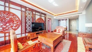 A traditional-style living room with a television, wooden furniture, and decorative wall panels. - Pujing Weiting Hotel (Jinkunqiao) (Tianjin)