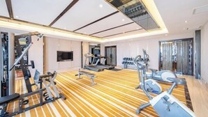 A modern gym with various exercise equipment, a wooden floor, and a large mirror. - Pujing Weiting Hotel (Jinkunqiao) (Tianjin)