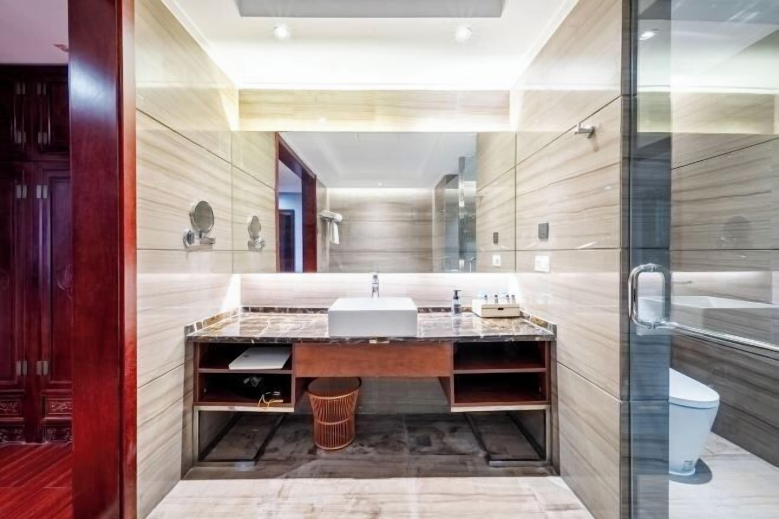 A modern bathroom with a large mirror, a sink, and a toilet.