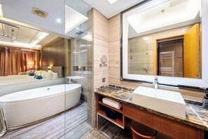 Ein modernes Badezimmer mit einem großen Spiegel, einer freistehenden Badewanne und einer Marmorplatte mit Waschbecken.