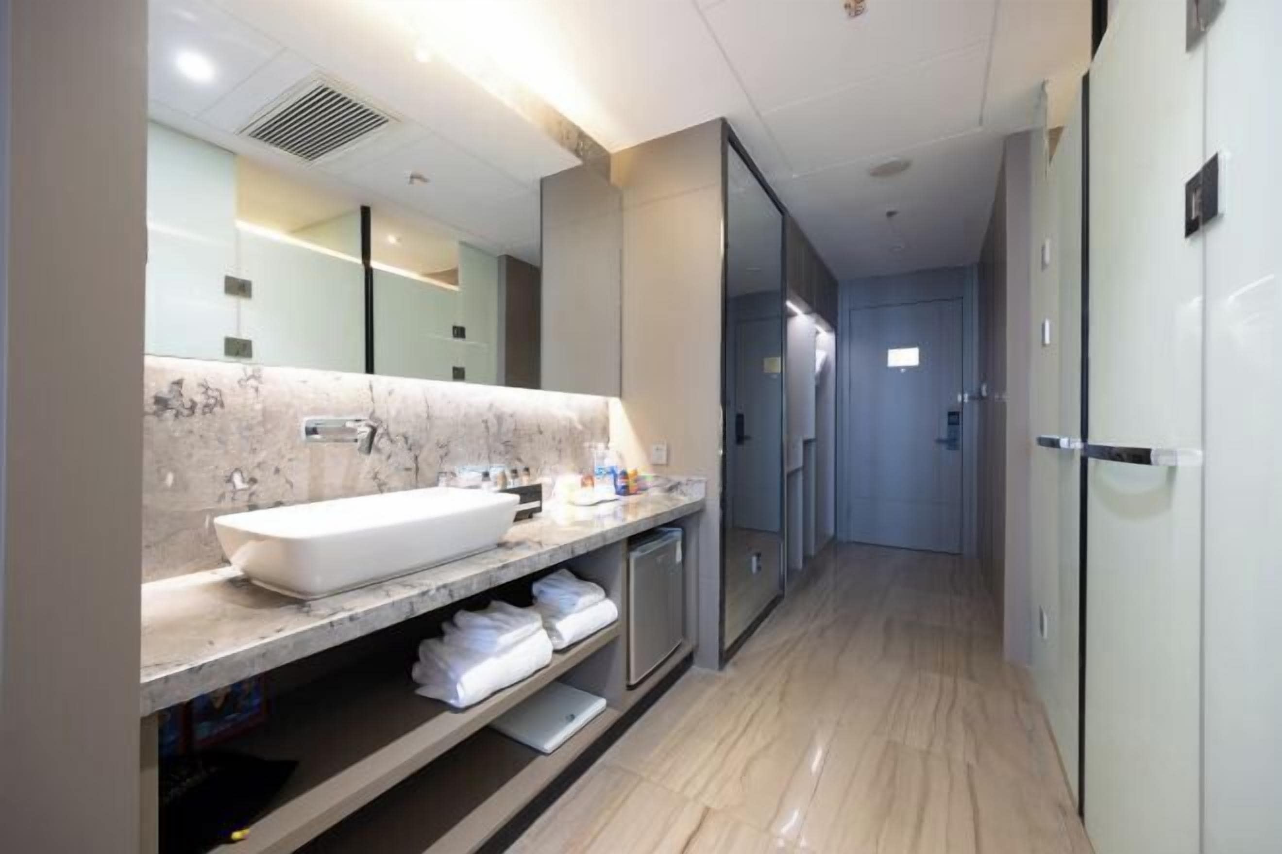 A modern bathroom with a large marble sink, a mirror, and a walk-in shower.