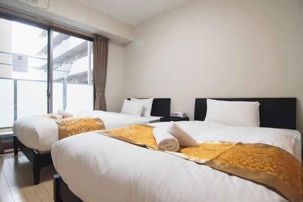 A hotel room with two beds, a window, and a view of the outside.