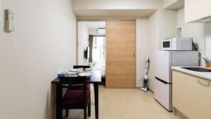 A compact kitchen with a microwave, refrigerator, and a dining area with a table and chairs. - toho residence (Osaka)