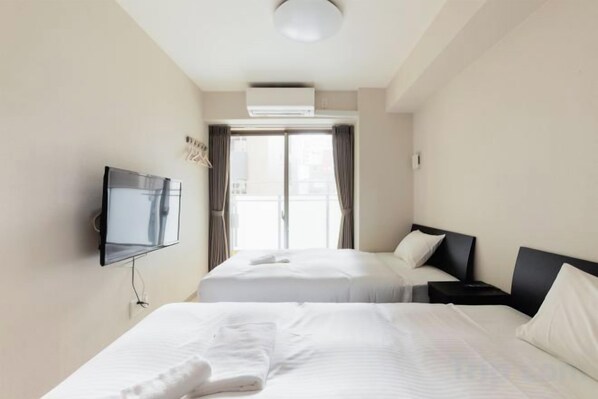 A hotel room with two beds, a TV, and a view of the outdoors. - toho residence (Osaka)