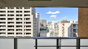 A view from a balcony with a cityscape, including high-rise buildings and a clear sky. - toho residence (Osaka)