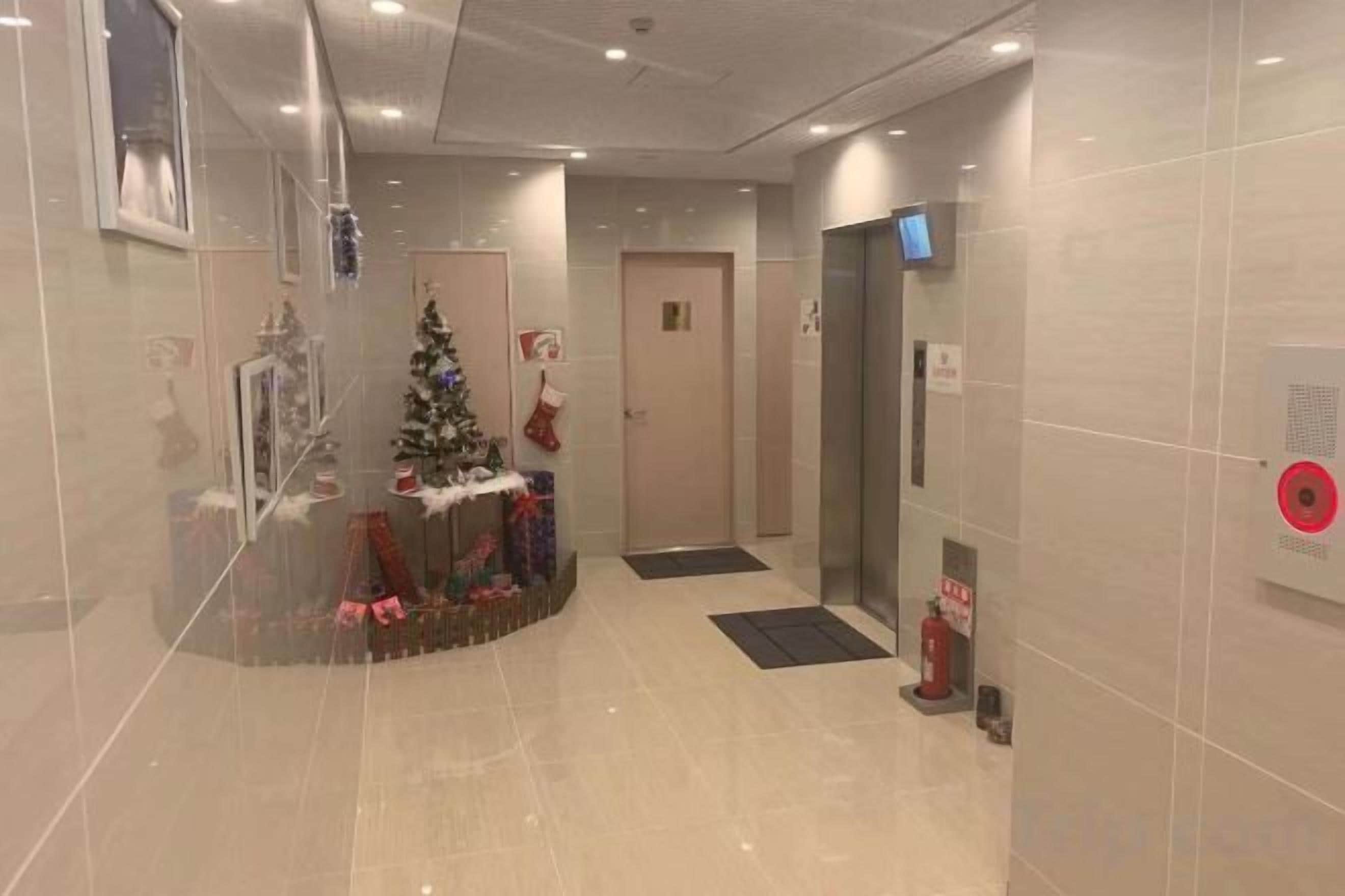 A corridor with a Christmas tree and presents, an elevator, and a fire alarm.
