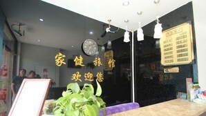 A reception area with a reception desk, a clock, and a sign indicating a registration area. - Jiajian Hostel (Shanghai)