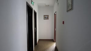 A narrow hallway with patterned flooring, a framed picture on the wall, and two doors. - Jiajian Hostel (Shanghai)