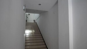 A narrow, well-lit stairway with a handrail, leading to a landing with a door. - Jiajian Hostel (Shanghai)