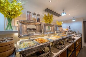 Un buffet proposant différents postes de service, avec une variété de plats présentés dans des récipients en métal.