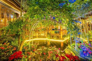 An indoor garden with a wooden bridge, a pond, and lush greenery. - Xin Zhoujia Courtyard (Lijiang)
