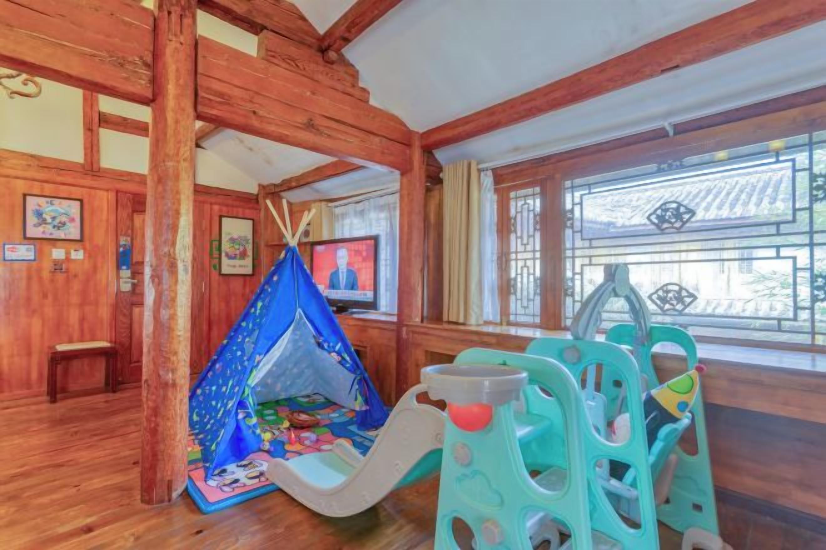 Interior de madeira com área de recreação, incluindo uma tenda e um escorrega.