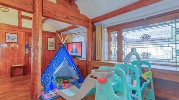Interior de madeira com área de recreação, incluindo uma tenda e um escorrega.