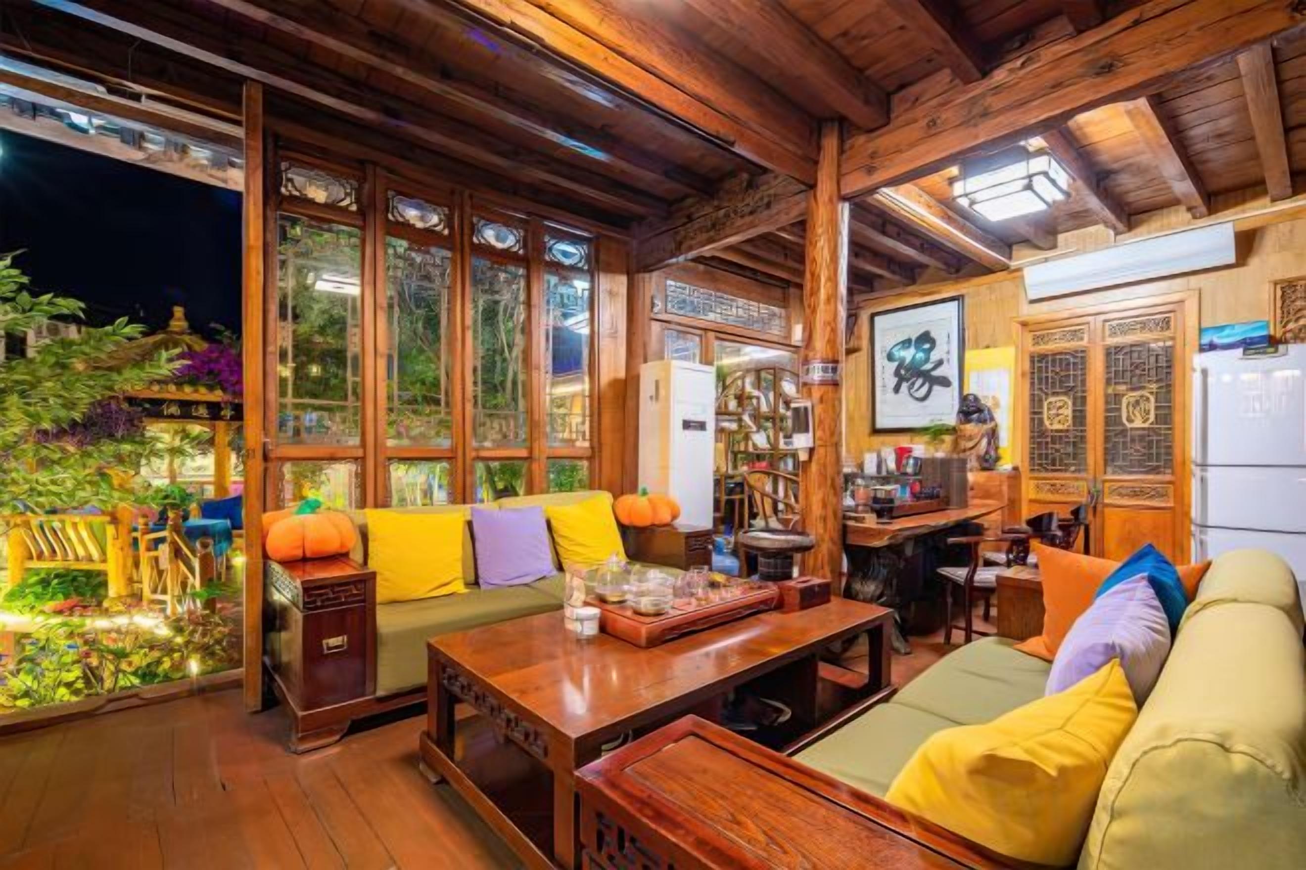 Um interior acolhedor com teto de madeira, um sofá com almofadas, uma mesa de jantar e uma área de cozinha.