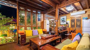 Um interior acolhedor com teto de madeira, um sofá com almofadas, uma mesa de jantar e uma área de cozinha.