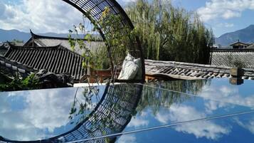 Pátio chinês tradicional com reflexo nítido na água, cercado por edifícios com telhados de cerâmica.
