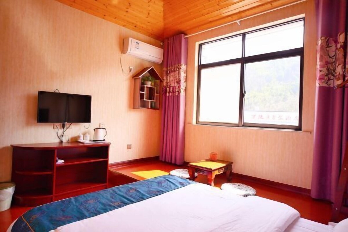 Une chambre d’hôtel avec un lit, une télévision, une petite table, une fenêtre et un plafond en bois.